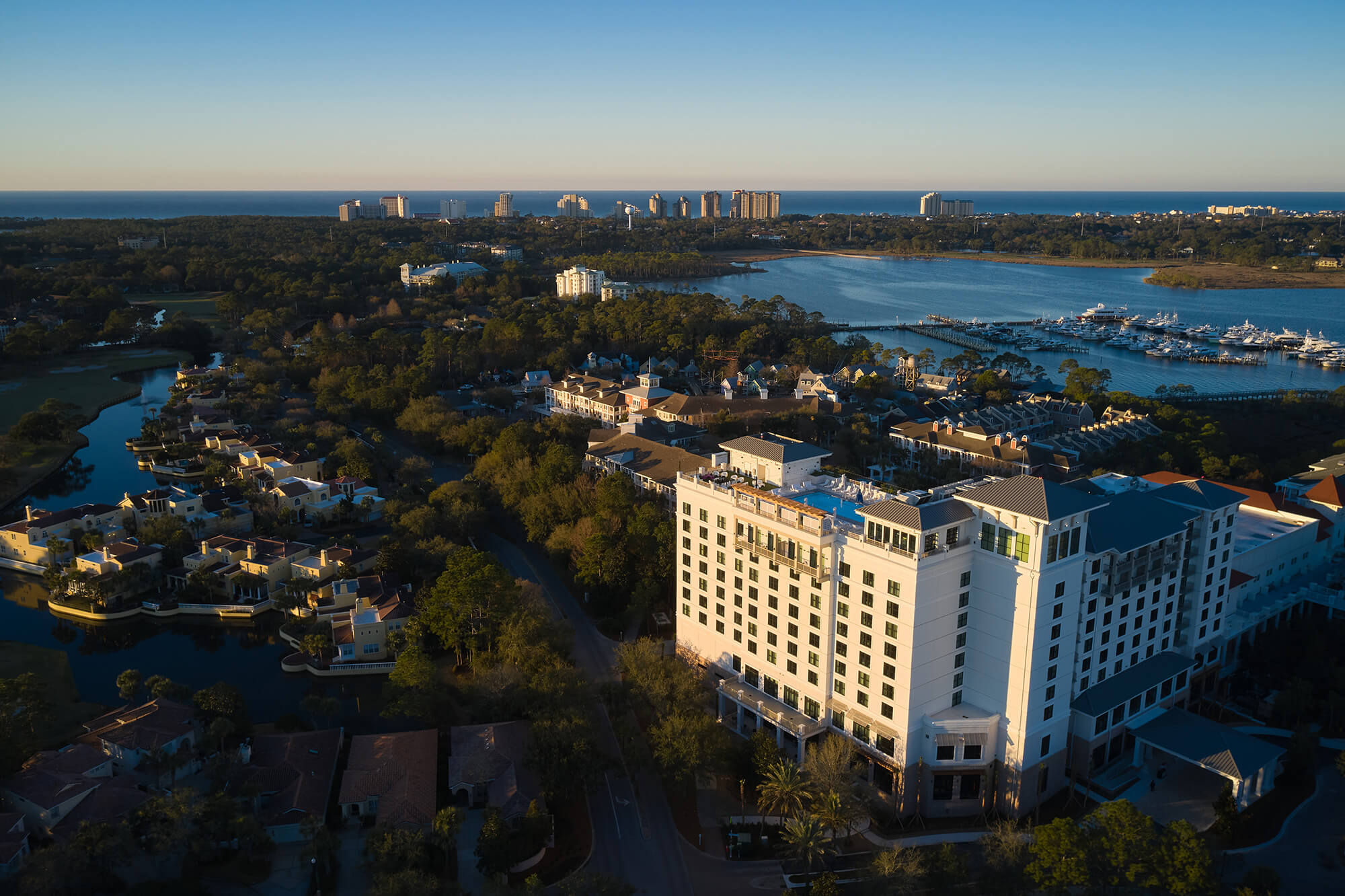 An aerial view of a sprawling resort complex lit up at dusk, with a lake in the background.