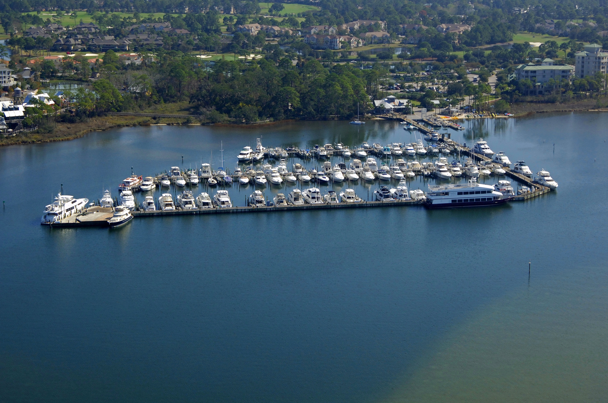 A tranquil marina filled with docked boats, surrounded by lush green trees.