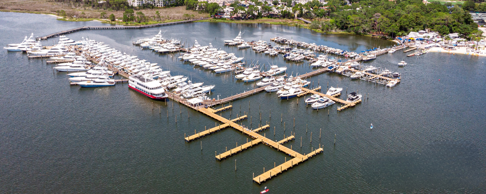 An aerial shot of a large marina filled with docked boats and yachts on a sunny day.