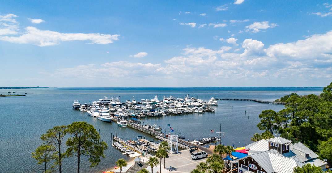 An aerial view of a large marina on a bright, sunny day with many boats docked.