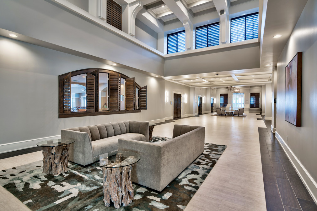 The elegant, long hallway of a modern hotel lobby with contemporary furniture and patterned carpeting.