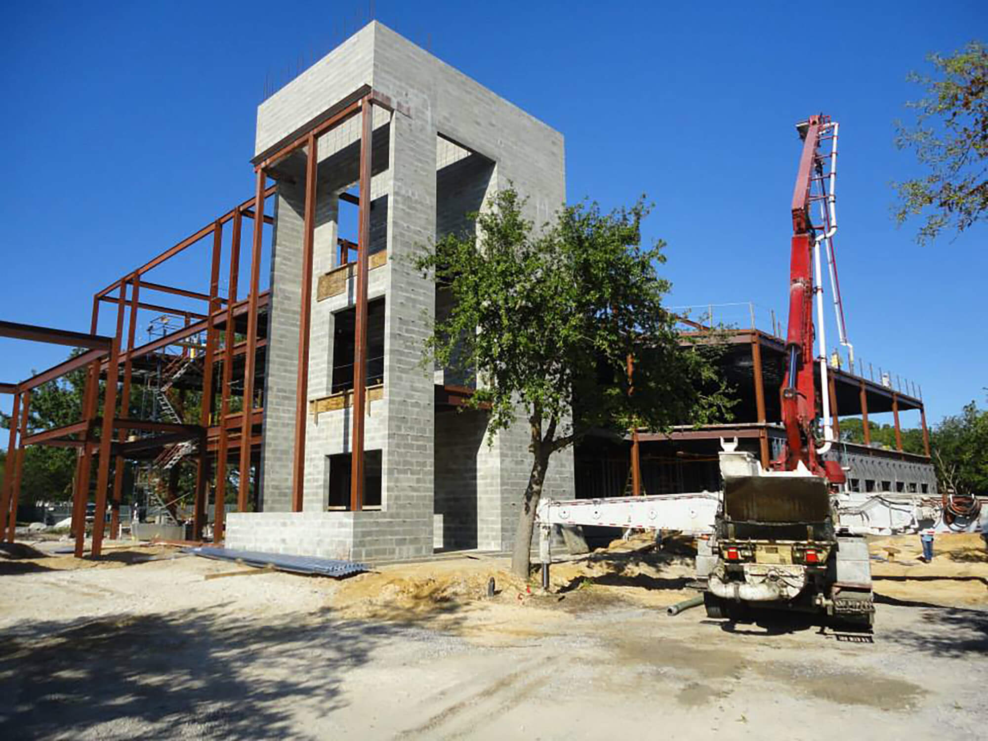 The steel frame of a multi-story building under construction, with a construction crane visible.