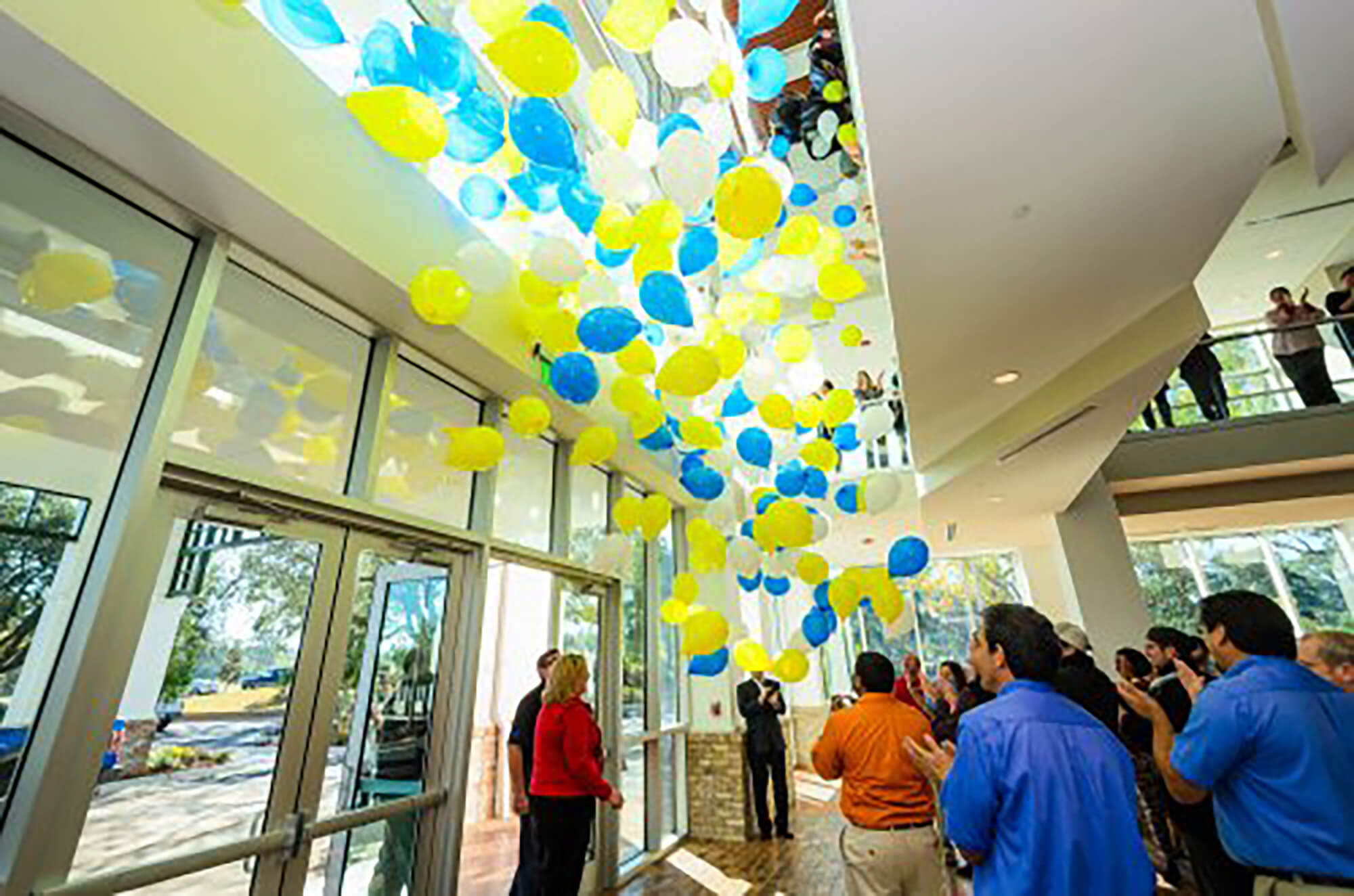 White, yellow and blue balloons descend from the ceiling of the Sandestin Welcome Center, with a crowd below