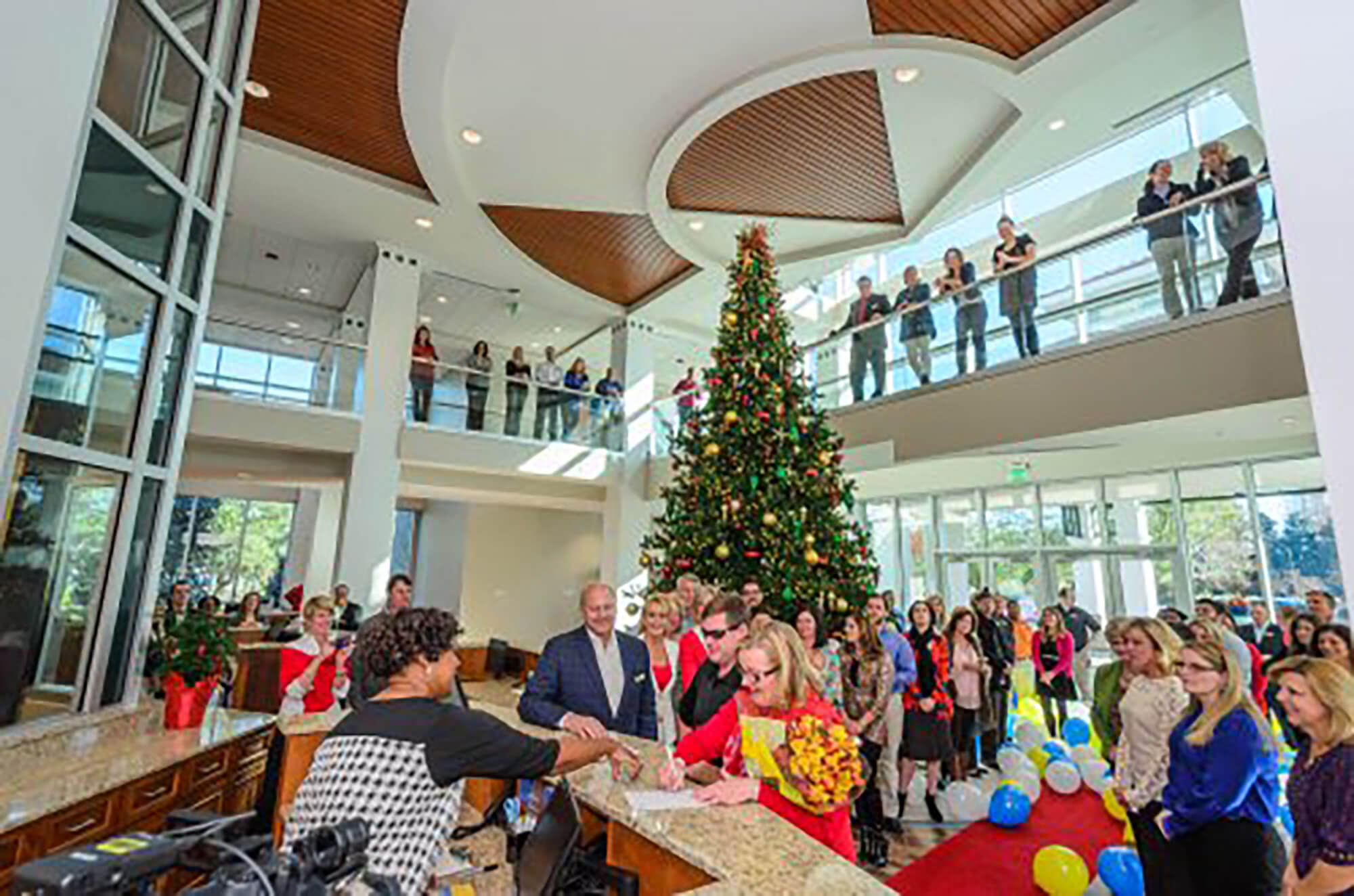 A bright airy atrium of the Sandestin Welcome Center, with a crowd gathered around a tall Christmas tree