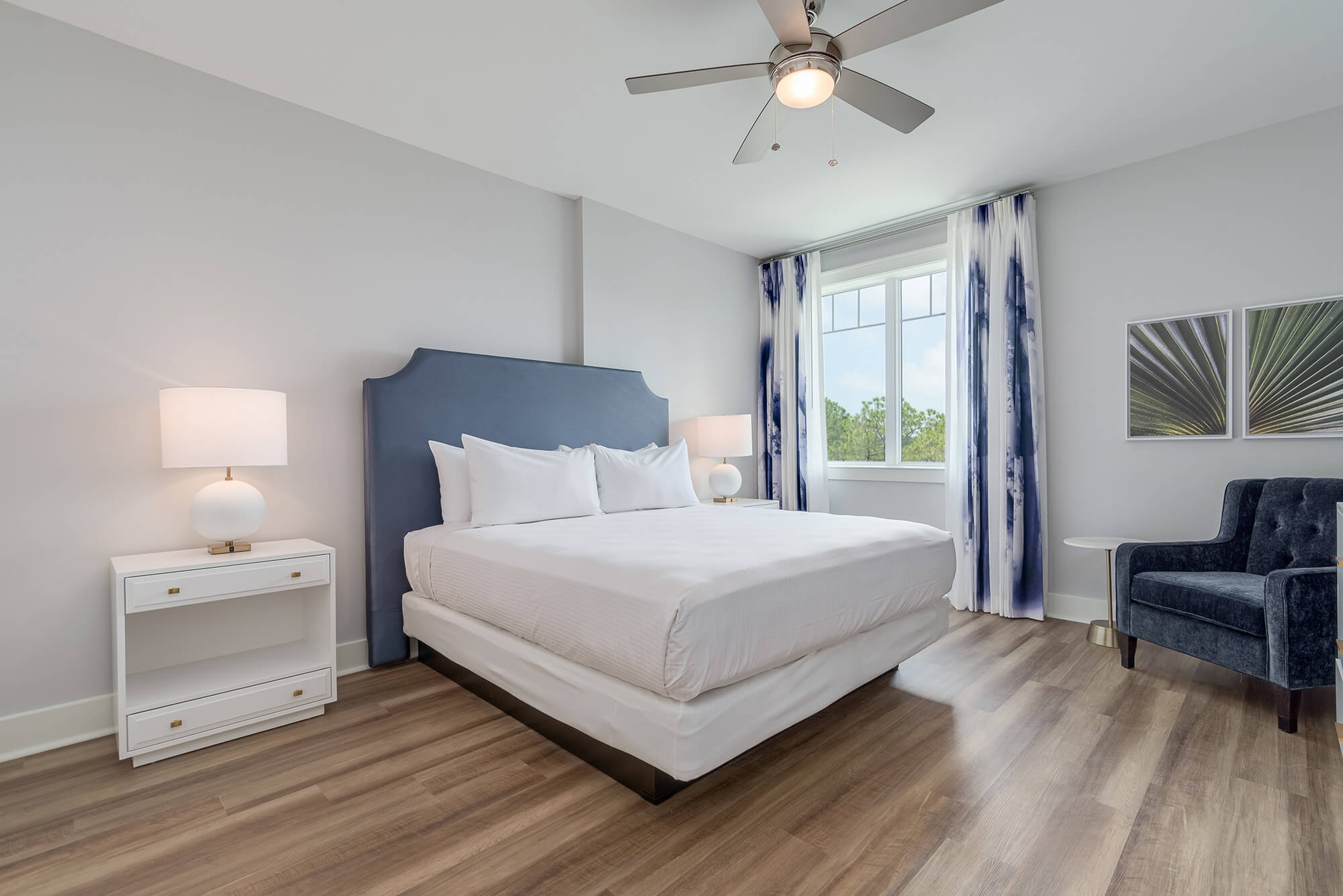 A clean and simple hotel bedroom with a made-up bed, a nightstand, and a ceiling fan.