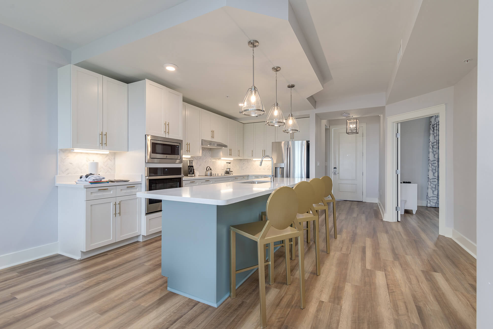 A bright and airy living room and kitchen area with white and blue decor and light wood floors.