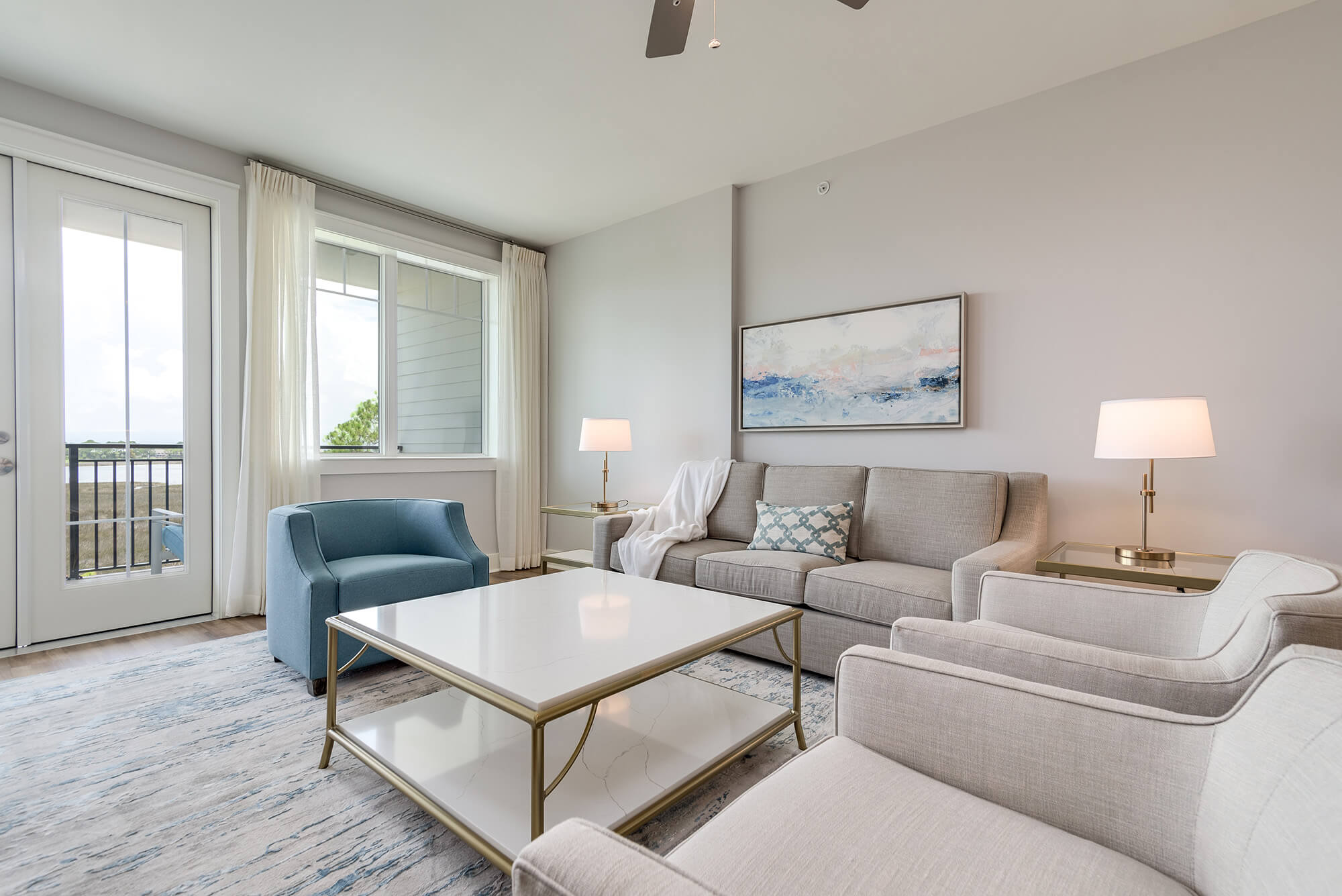 A bright and airy living room and kitchen area with white and blue decor and light wood floors.