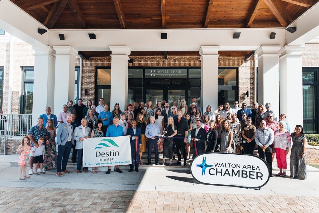 A large group of people gathered for a Chamber of Commerce ribbon-cutting event in a spacious, modern lobby.