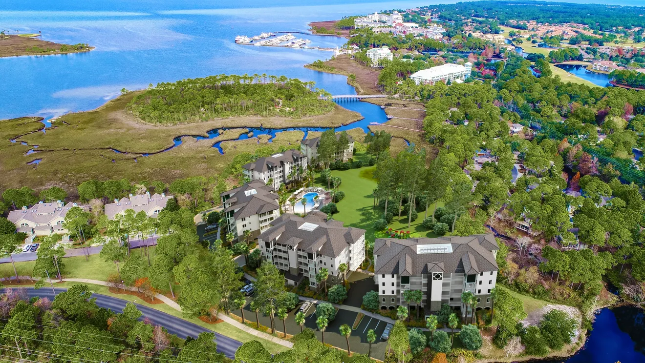 An aerial view of a coastal hotel and resort area, showing the buildings, golf course, and bay.