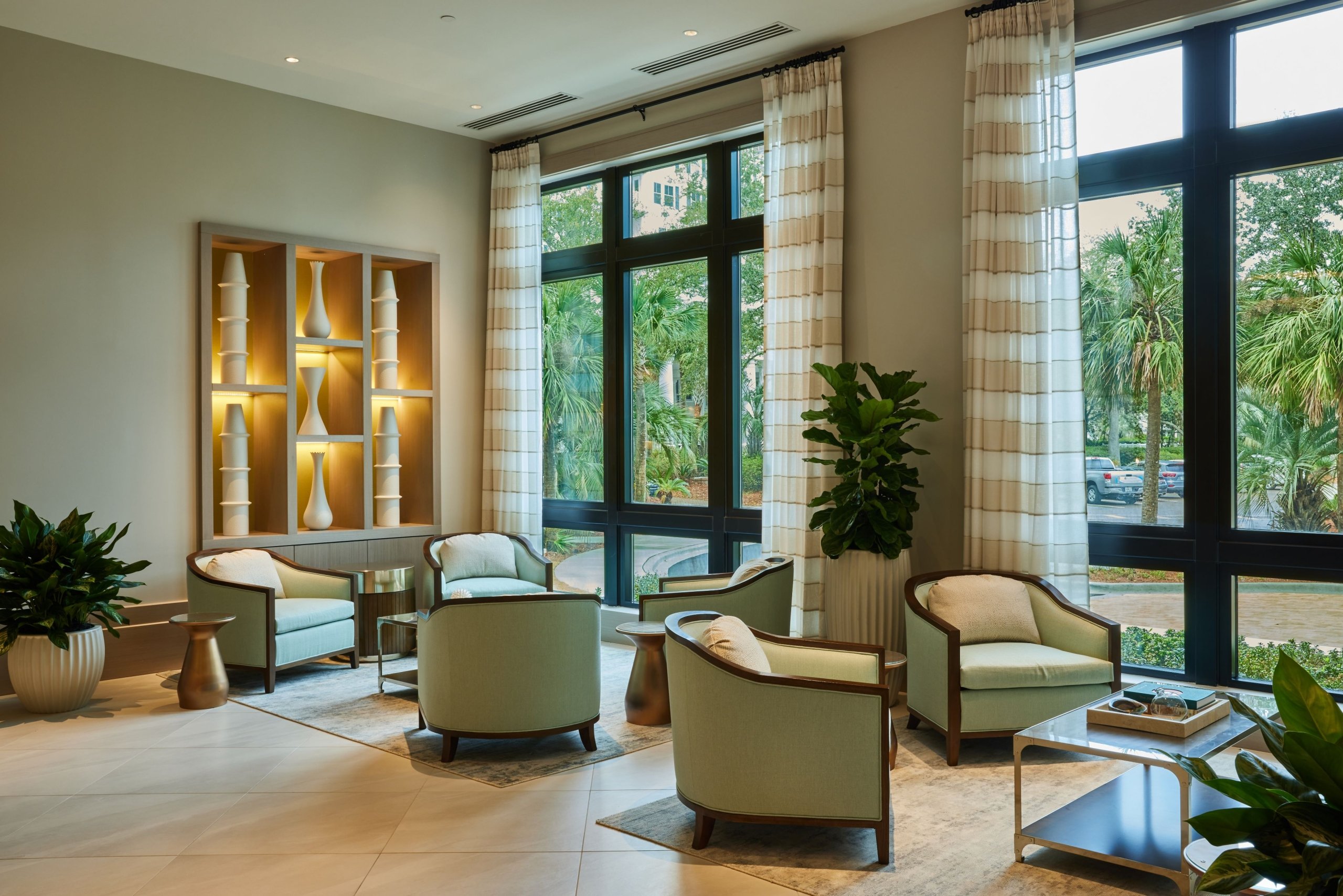 An elegant seating area with two armchairs and a small table next to a large window in a luxury home.