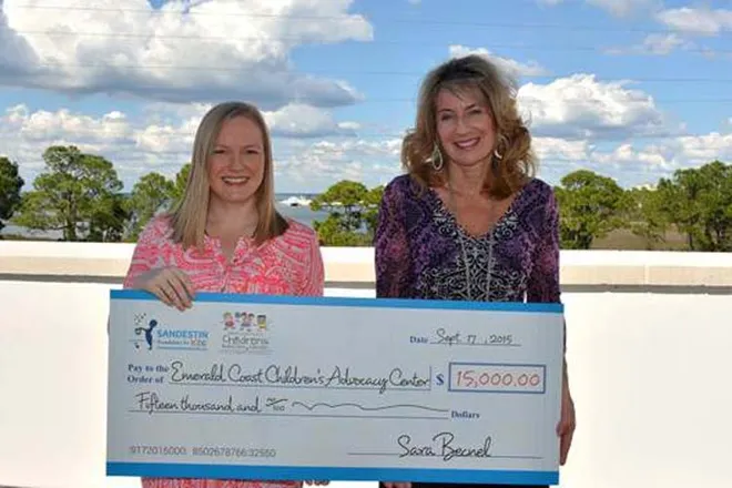 Two women hold a large ceremonial check for $15,000 from the Sandestin Foundation for Kids, payable to the Emerald Coast Children's Advocacy Center, dated September 17, 2015.